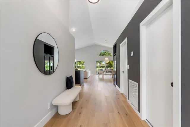 a view of a hallway with wooden floor and a bathroom