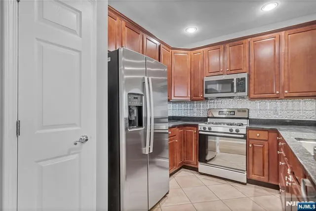 a kitchen with stainless steel appliances granite countertop a refrigerator stove and cabinets