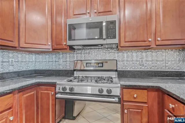 a kitchen with stainless steel appliances granite countertop white cabinets stove top oven and granite counter top