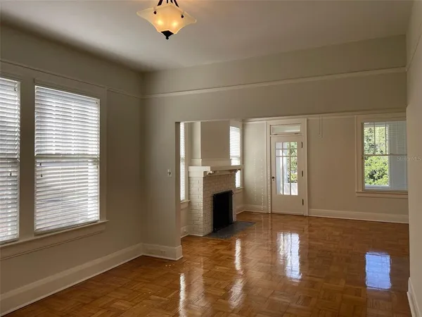 a view of an empty room with a window and wooden floor