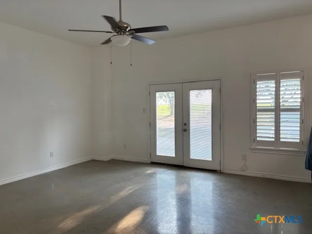 an empty room with wooden floor chandelier fan and windows