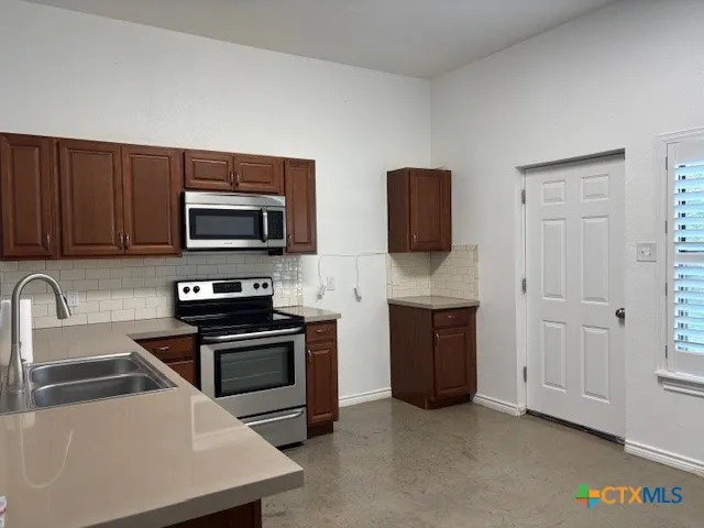 a kitchen with stainless steel appliances a stove microwave and sink