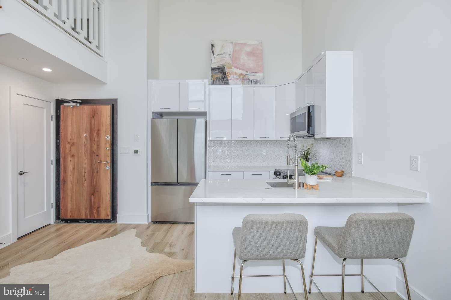 4328 Georgia Avenue Northwest, Unit 401 Washington, DC 20011 - Photo 13 of 32 a kitchen with stainless steel appliances a sink a refrigerator a stove a dining table and chairs with wooden floor