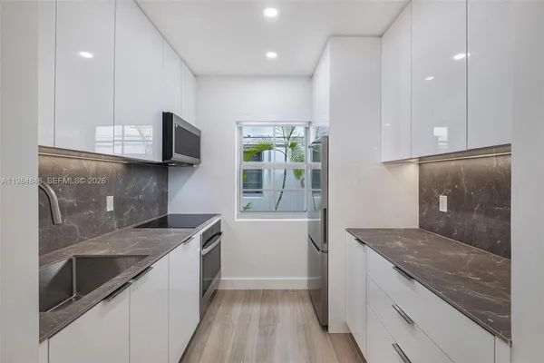 a kitchen with kitchen island granite countertop a sink and a stove top oven