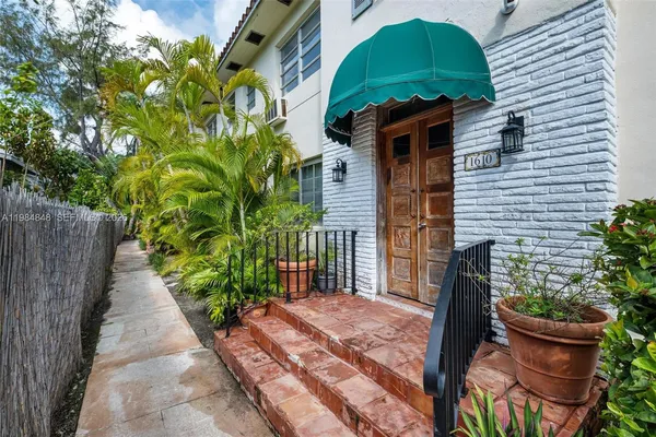 a front view of a house with a yard and potted plants