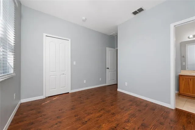 a view of an empty room with window and wooden floor