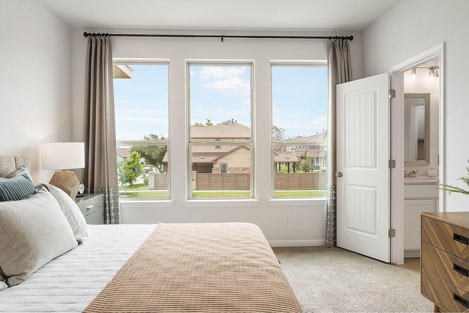 20603 B Combine Path Pflugerville, TX 78660 - Photo 13 of 19 Three tall windows welcome natural light into this comfortable sleeping space, complemented by plush carpeting.