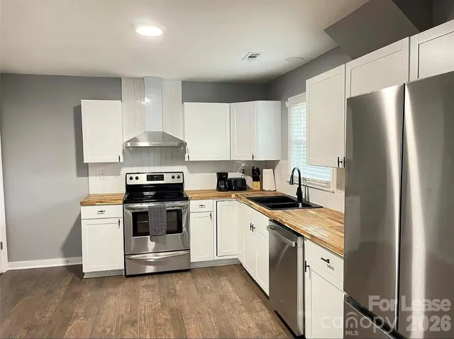 a kitchen with stainless steel appliances a sink a stove a refrigerator and white cabinets