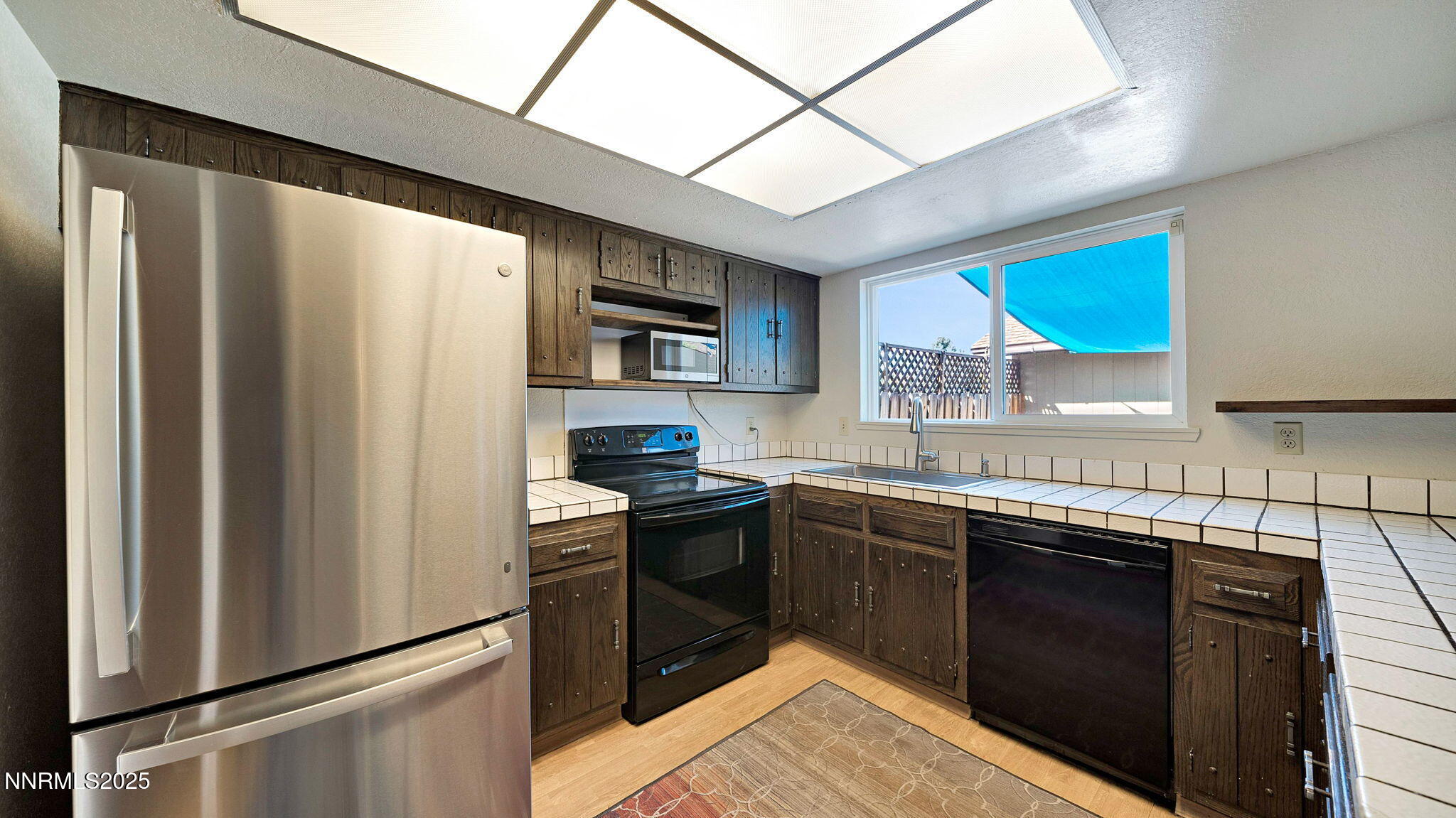 1515 Foster Drive Reno, NV 89509 - Photo 26 of 50 a kitchen with stainless steel appliances granite countertop a refrigerator a sink dishwasher a stove top oven a washer and dryer with wooden floor