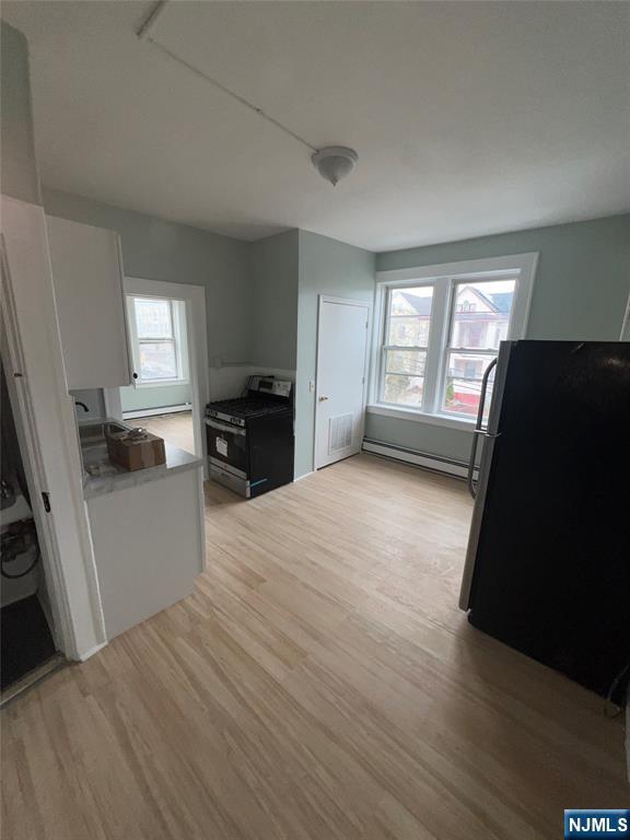 193 President Street, Unit 9 Passaic, NJ 07055 - Photo 7 of 11 a kitchen with a refrigerator a stove top oven a sink dishwasher and wooden floor