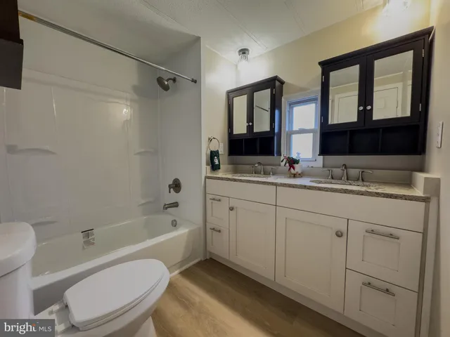 a bathroom with a granite countertop sink toilet a mirror a bathtub and shower