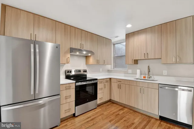 a kitchen with stainless steel appliances a sink cabinets and a wooden floor