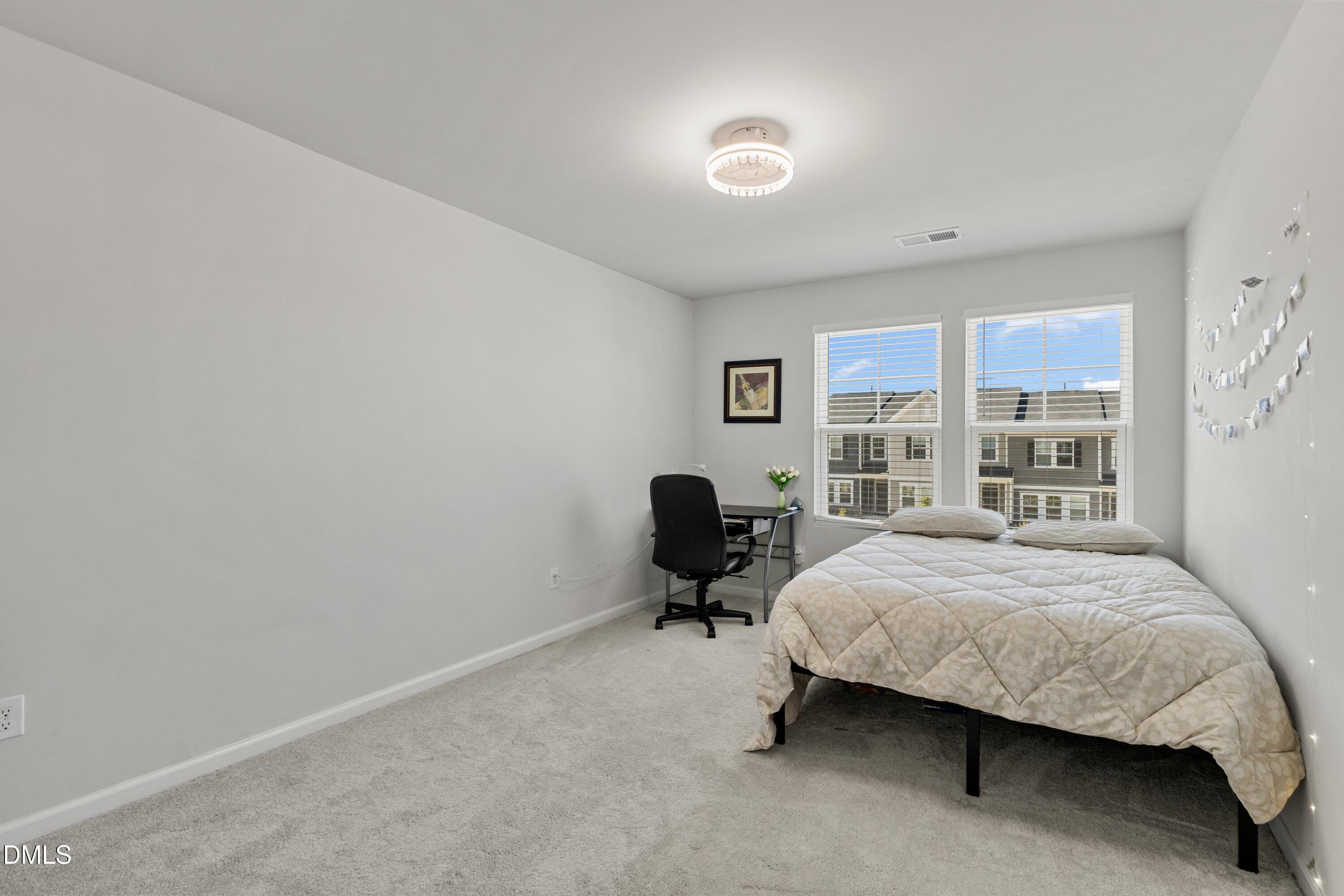 1811 Aspen River Lane Apex, NC 27502 - Photo 30 of 53 a bedroom with a bed lamp on desk and a window