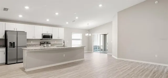 a kitchen with stainless steel appliances granite countertop a refrigerator a stove top oven a sink and dishwasher with wooden floor