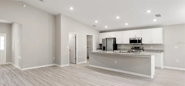 a kitchen with stainless steel appliances granite countertop a refrigerator and a stove top oven