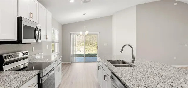 a kitchen with stainless steel appliances granite countertop a stove a sink and a refrigerator