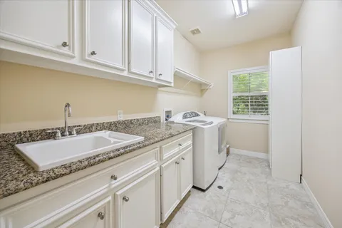 a utility room with granite countertop a sink and a stove