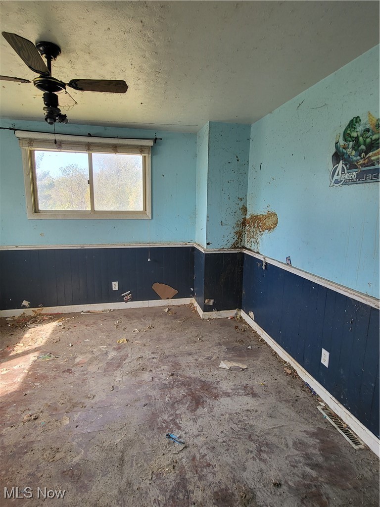 43650 Lafferty Oco Road Flushing, OH 43977 - Photo 11 of 23 Unfurnished room with wainscoting, wood walls, a textured ceiling, and ceiling fan