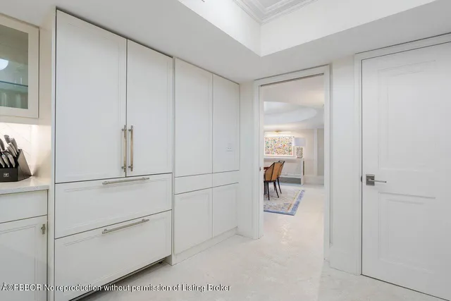 a hallway with white doors and chandelier