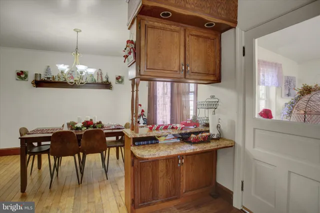 a kitchen with stainless steel appliances granite countertop a stove top oven a dining table and chairs with wooden floor