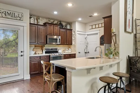 a kitchen with a sink a stove a refrigerator cabinets and wooden floor