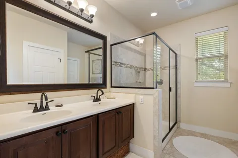 a bathroom with a double vanity sink toilet mirror and shower