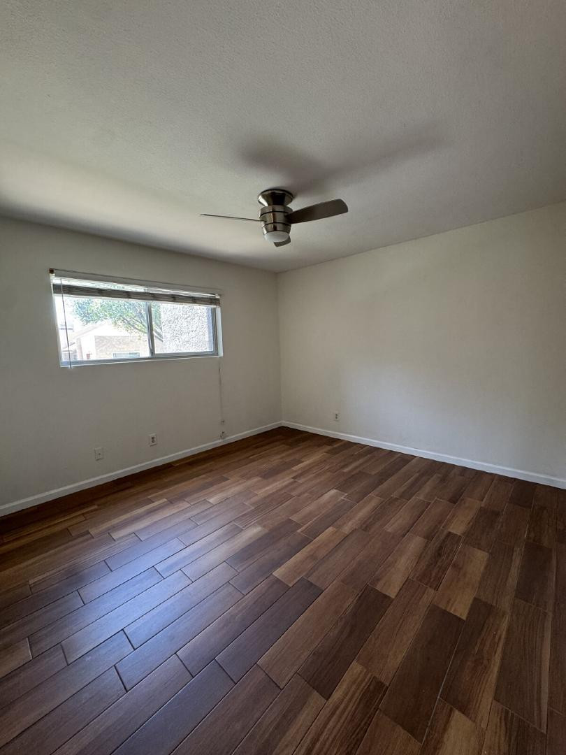 5525 East Thomas Road, Unit F1 Phoenix, AZ 85018 - Photo 11 of 14 an empty room with wooden floor ceiling fan and windows
