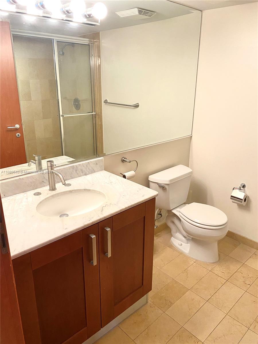 9499 Collins Avenue, Unit 309 Surfside, FL 33154 - Photo 11 of 16 a bathroom with a sink a toilet and mirror