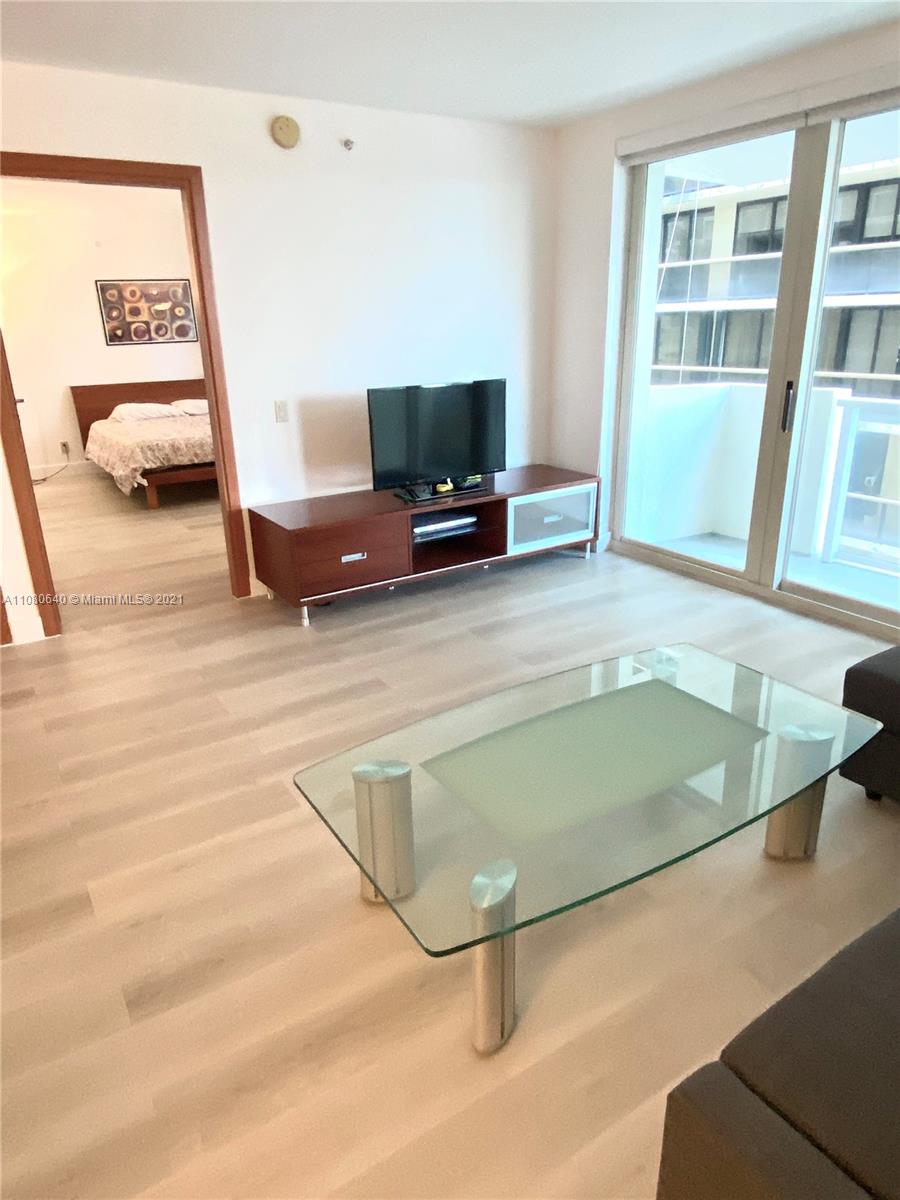 9499 Collins Avenue, Unit 309 Surfside, FL 33154 - Photo 13 of 16 a living room with a flat screen tv and gym equipment