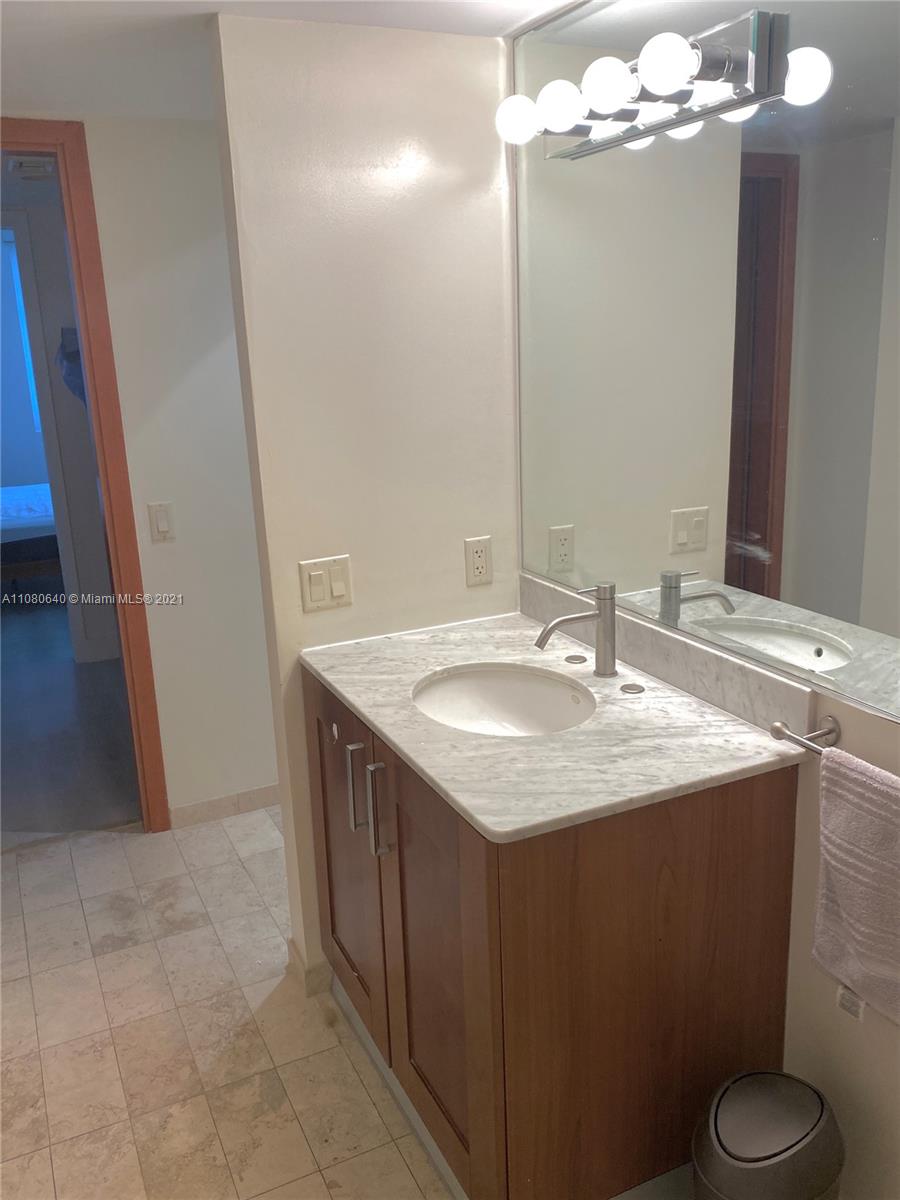9499 Collins Avenue, Unit 309 Surfside, FL 33154 - Photo 10 of 16 a bathroom with a granite countertop sink a toilet and a mirror