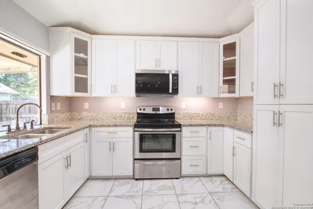 a kitchen with white cabinets and a large window