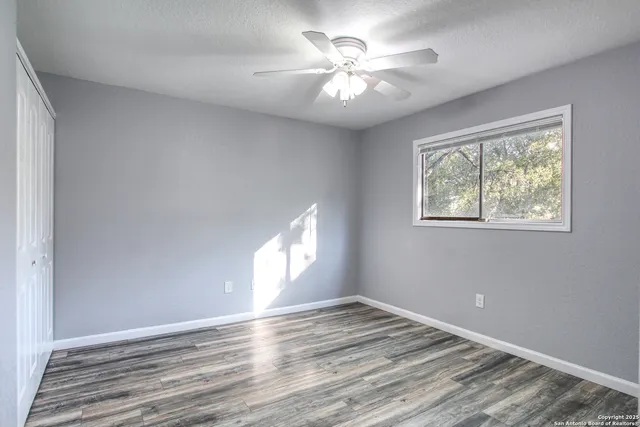 a view of empty room with wooden floor and fan