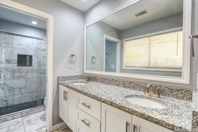 a bathroom with a granite countertop sink and a mirror