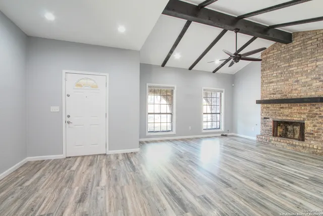 a view of an empty room with window and fireplace