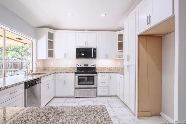 a kitchen with white cabinets appliances and a sink