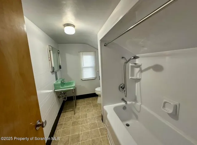 a bathroom with a tub sink and mirror