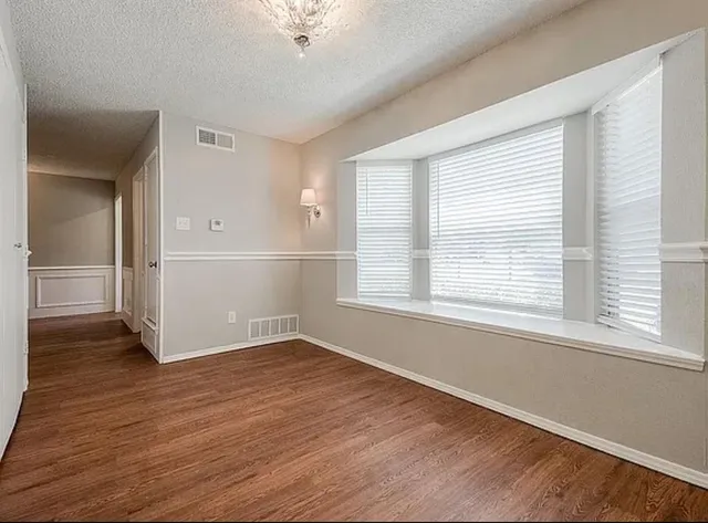 an empty room with wooden floor cabinet and windows