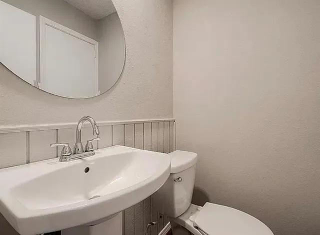 a bathroom with a sink a toilet and a mirror