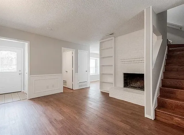 an empty room with wooden floor and fireplace
