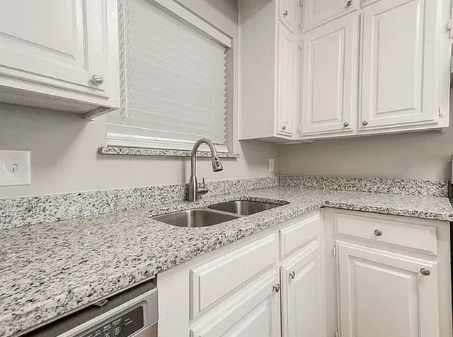 a kitchen with granite countertop white cabinets and a sink