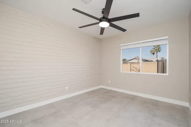an empty room with window and ceiling fan