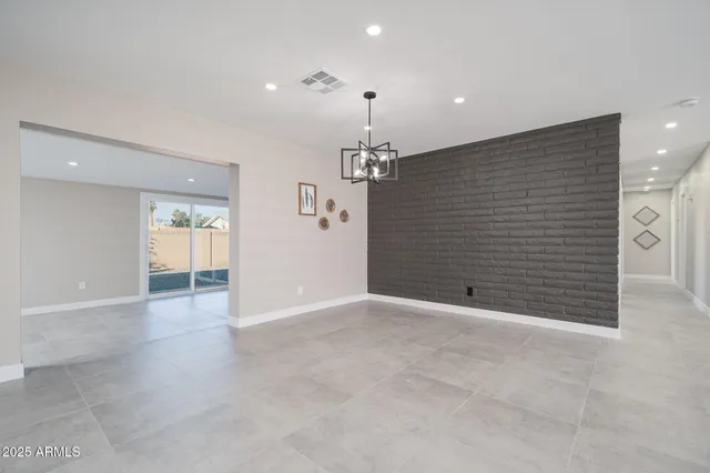 a view of an empty room with chandelier and entryway