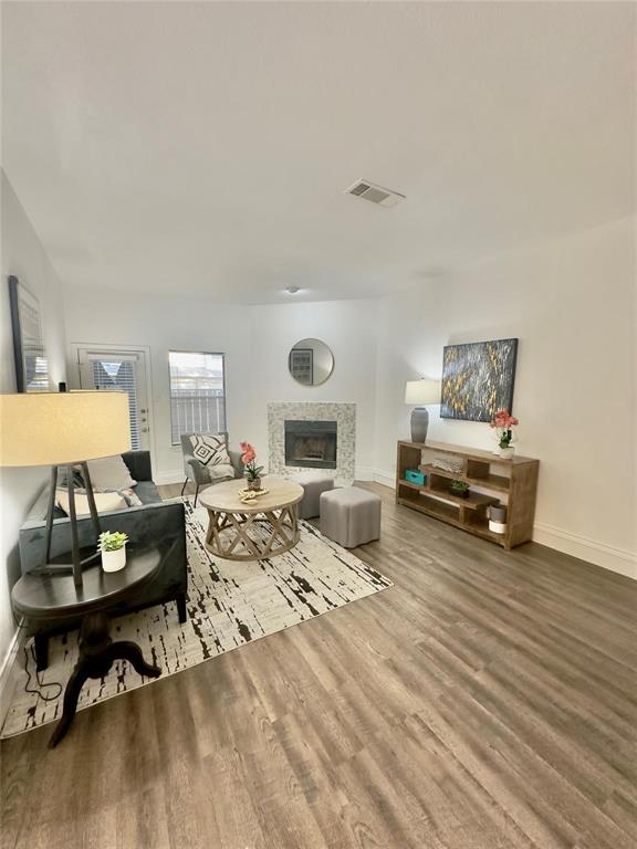 7340 Skillman Street, Unit 405 Dallas, TX 75231 - Photo 3 of 18 Living area featuring wood-finish flooring, a tiled fireplace, and white baseboards