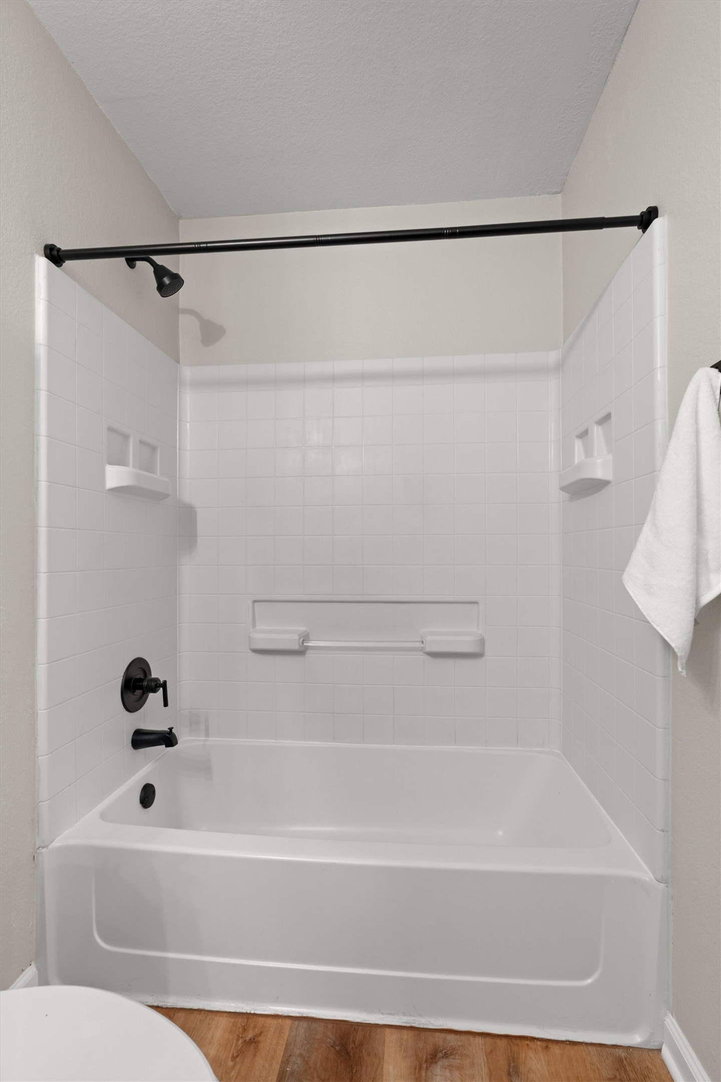 724 Lavaca Loop Elgin, TX 78621 - Photo 20 of 40 White tiled walls surround a classic tub and shower combination finished with dark metal hardware.