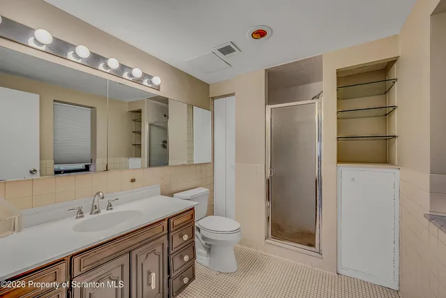 a bathroom with a granite countertop sink a toilet a mirror and shower