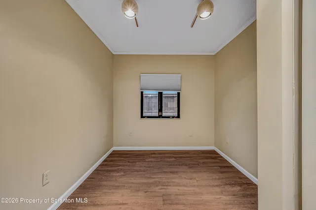 a view of an empty room with wooden floor and a window