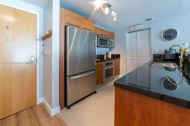 a kitchen with stainless steel appliances granite countertop a refrigerator a stove and a sink with wooden floor