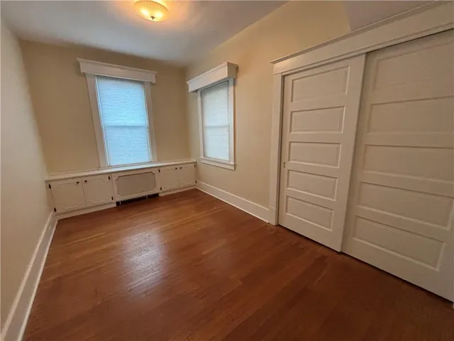 an empty room with wooden floor and cabinet
