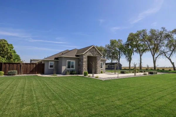 a view of a house with a big yard and palm trees