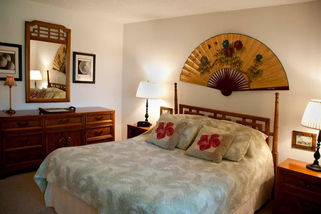 a bedroom with a bed and a lamp on dresser